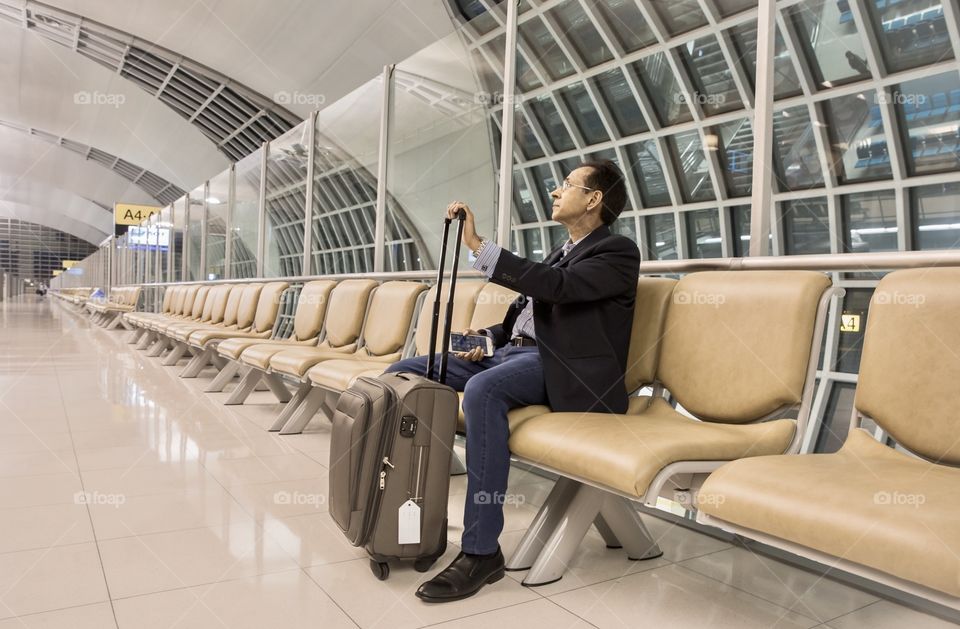 Businessman with his luggage waiting to board the airplane 
