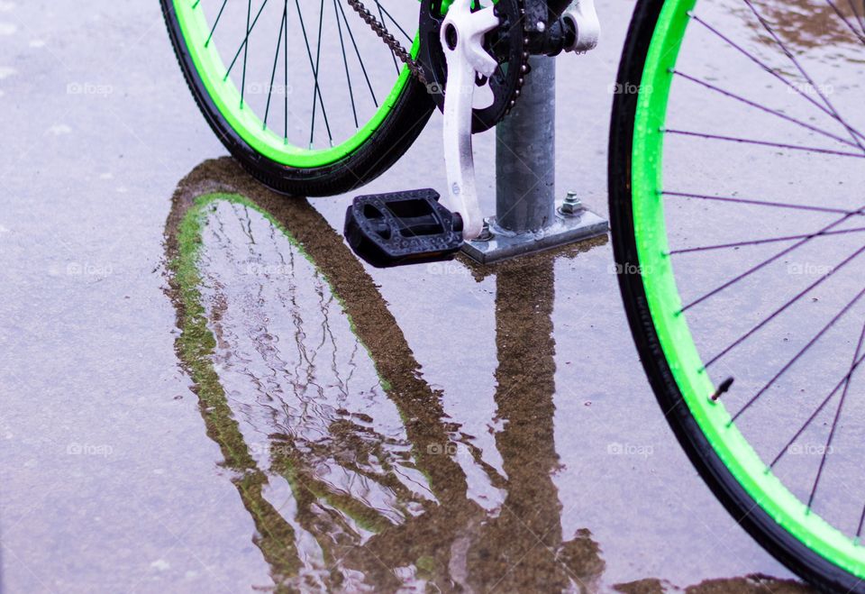 Bright green bike wheels. Bike with bright green rims and it's reflection on the wet pavement.