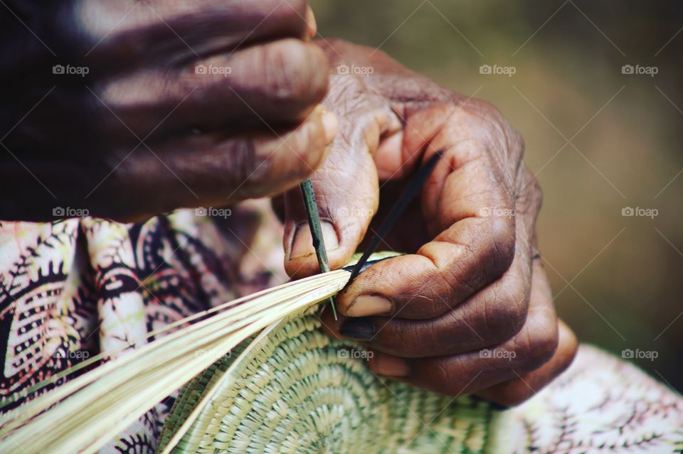 A woman's hands weaving a basket in Uganda.