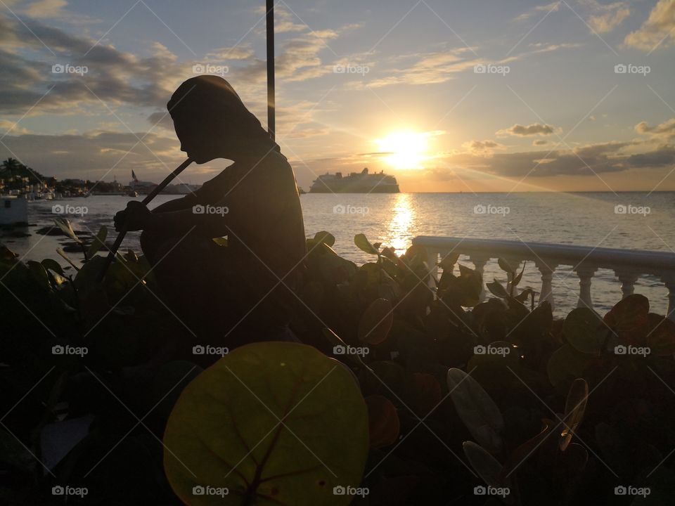 Beatiful and Amazing sunset in our paradise, cozumel Island, México. So lovely, with a pretty statue and a cruise ship on the ocean. The most Beatiful sunsets are in this big Island in the mexican caribbean.