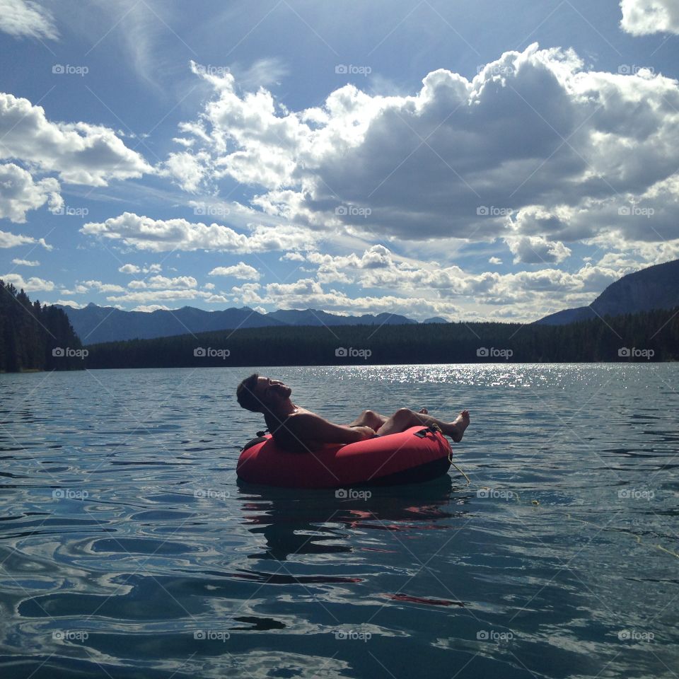 Shirtless man resting on inflatable boat