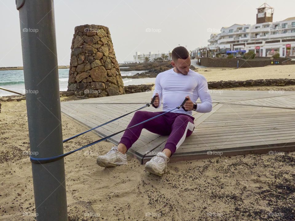 chico joven entrenando en la calle en exteriores, usando bandas elásticas y realizando ejercicios variados