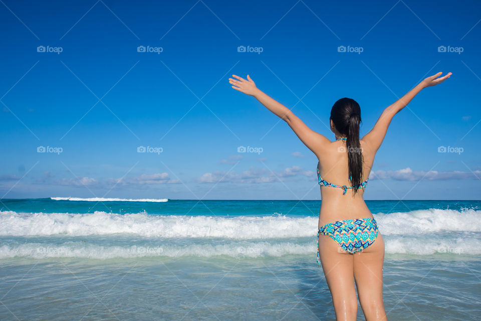 Beautiful lady extending arms on beach 