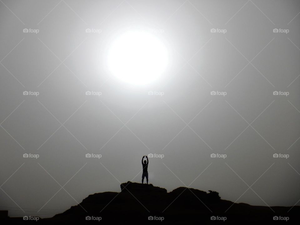 silohuette a man doing karate in front of the sun