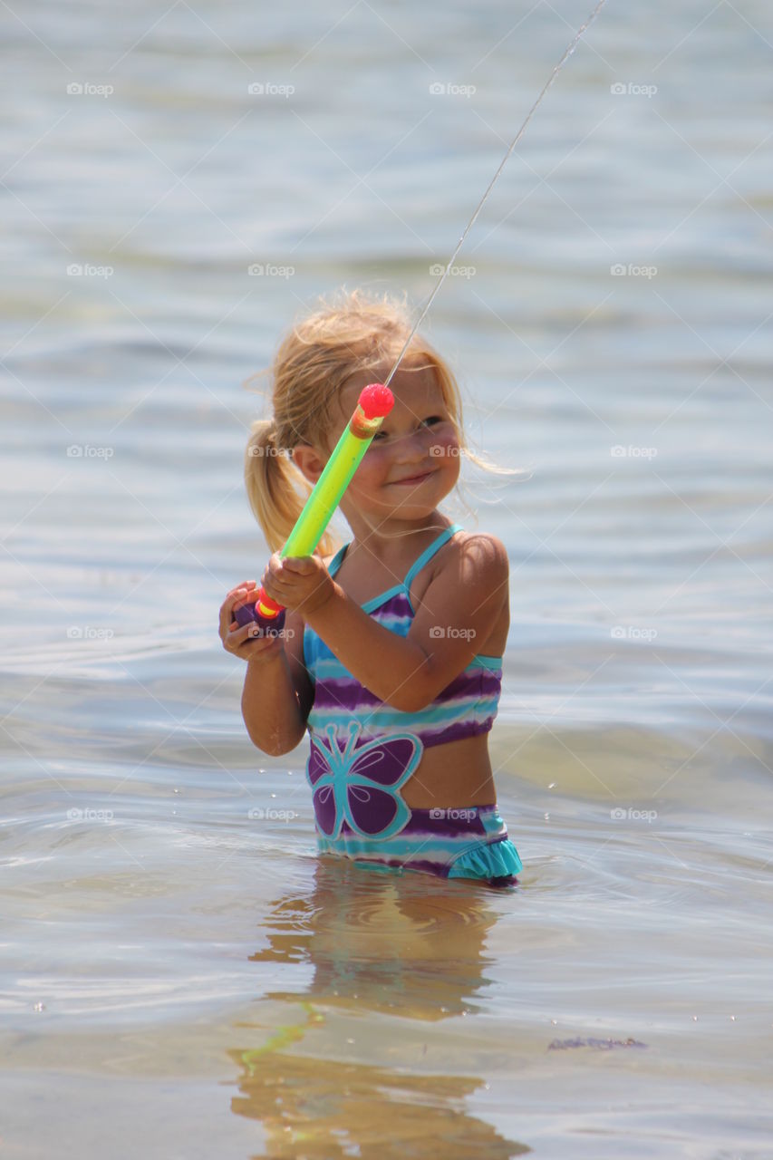 Little girl playing with water gun in sea