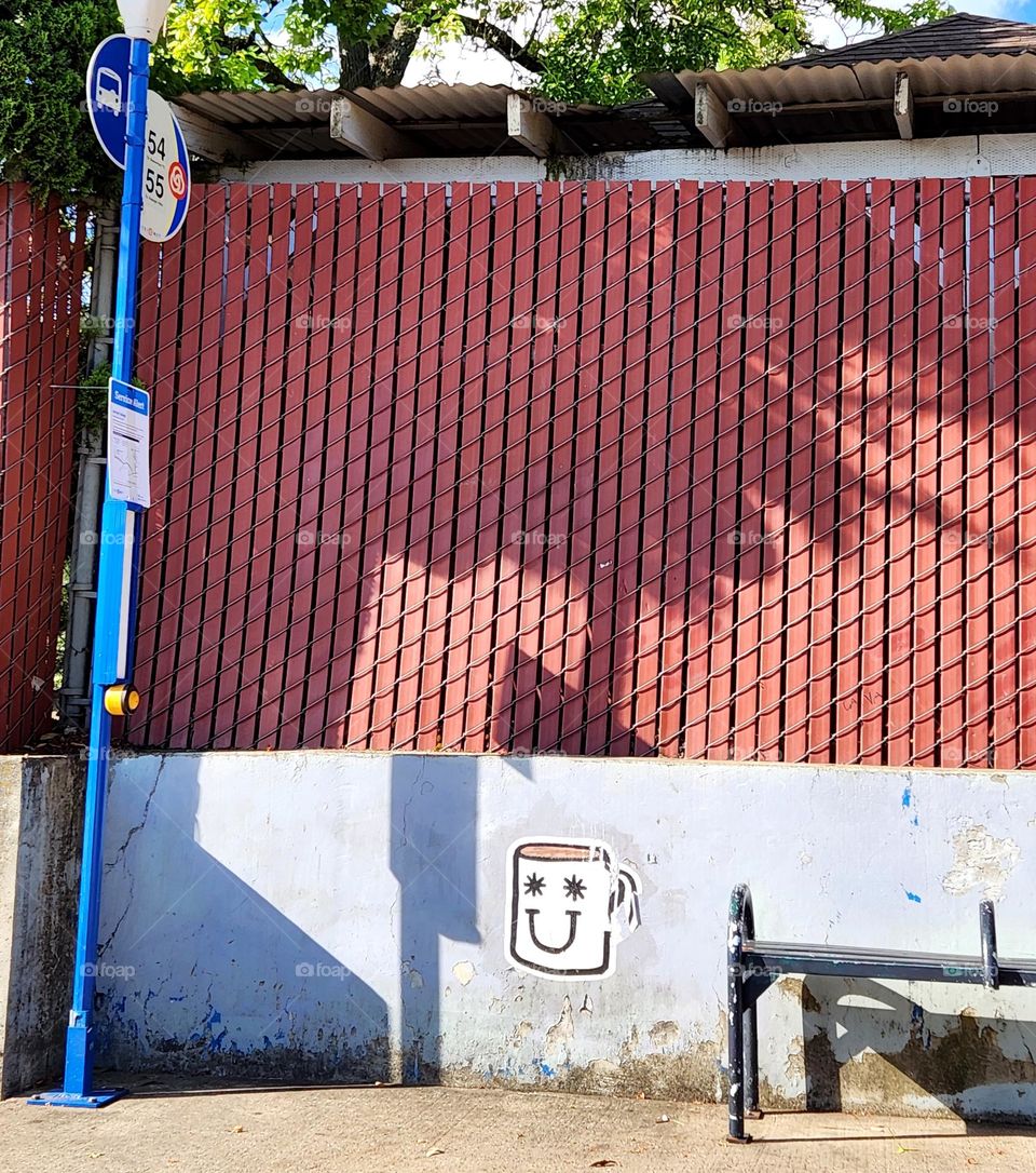 bus stop in Oregon on a sunny weekday afternoon with an eye-catching happy face mug on the wall