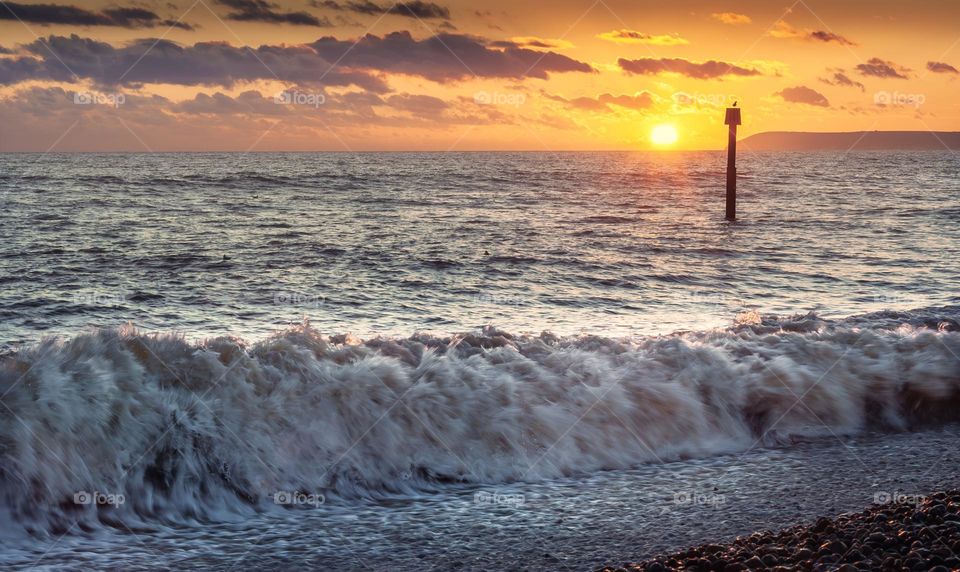 Waves crash on the beach at Bexhill as the sun sets over the English Channel.