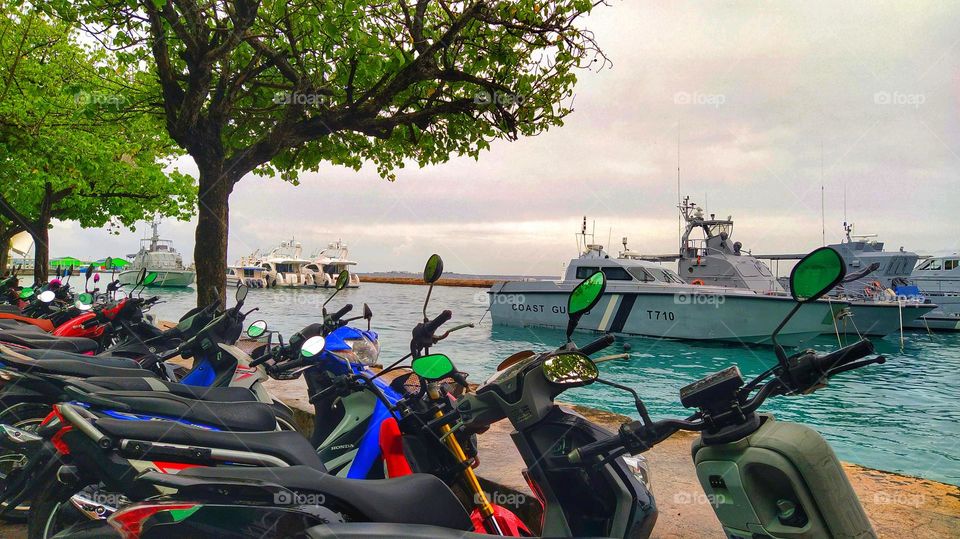 Scooters parked in the seaport with beautiful ships in the sea