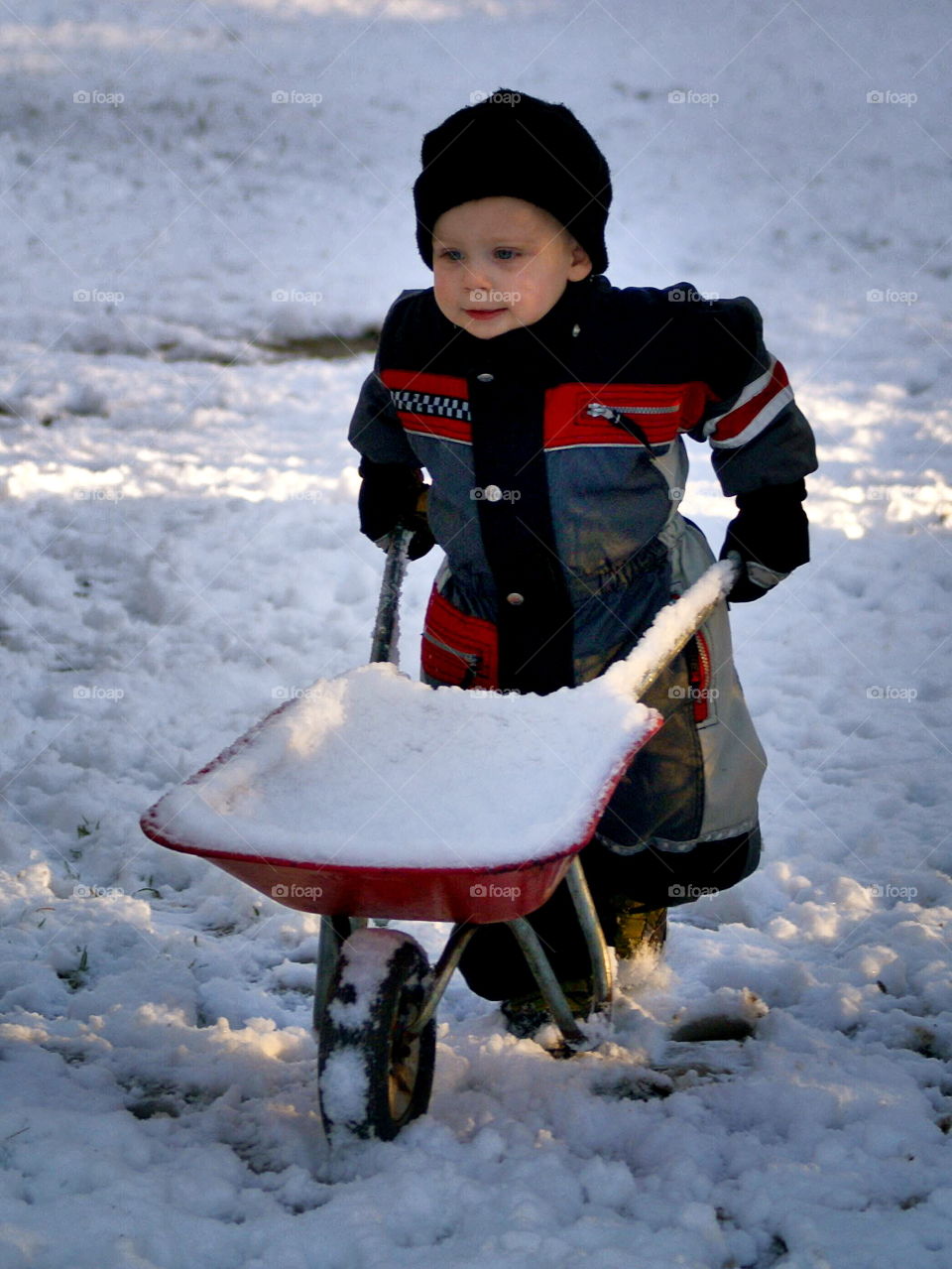 Little girl pushing snow cart