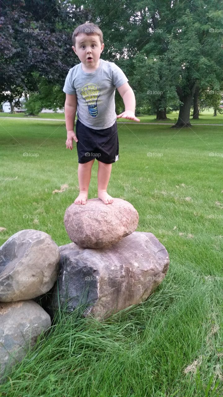 A little boy standing on stone at park