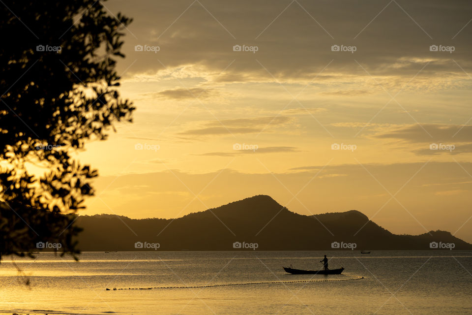 fisherman in the sea on a background of mountains during sunset