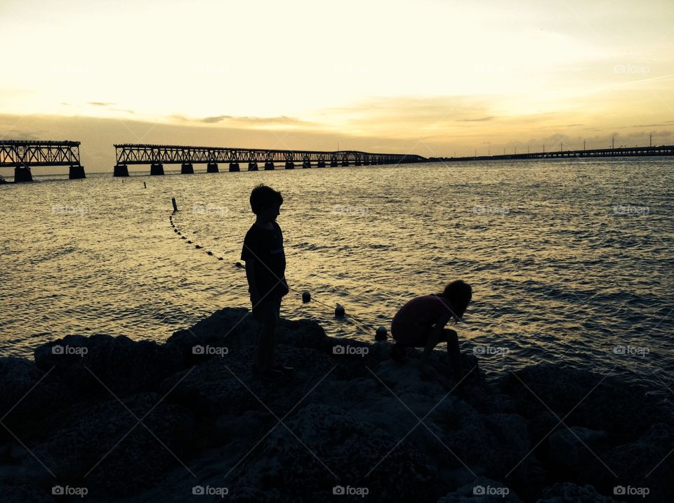 Backlit kids at sunset with old bridge to key west in background 