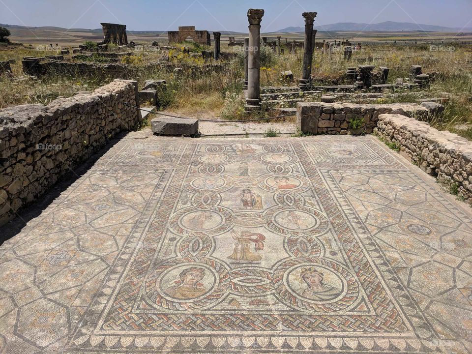 Beautiful Ceramic Mosaic with People/Ancient Gods and Columns in the Background at the Ancient Roman Ruins of Volulibis in Morocco
