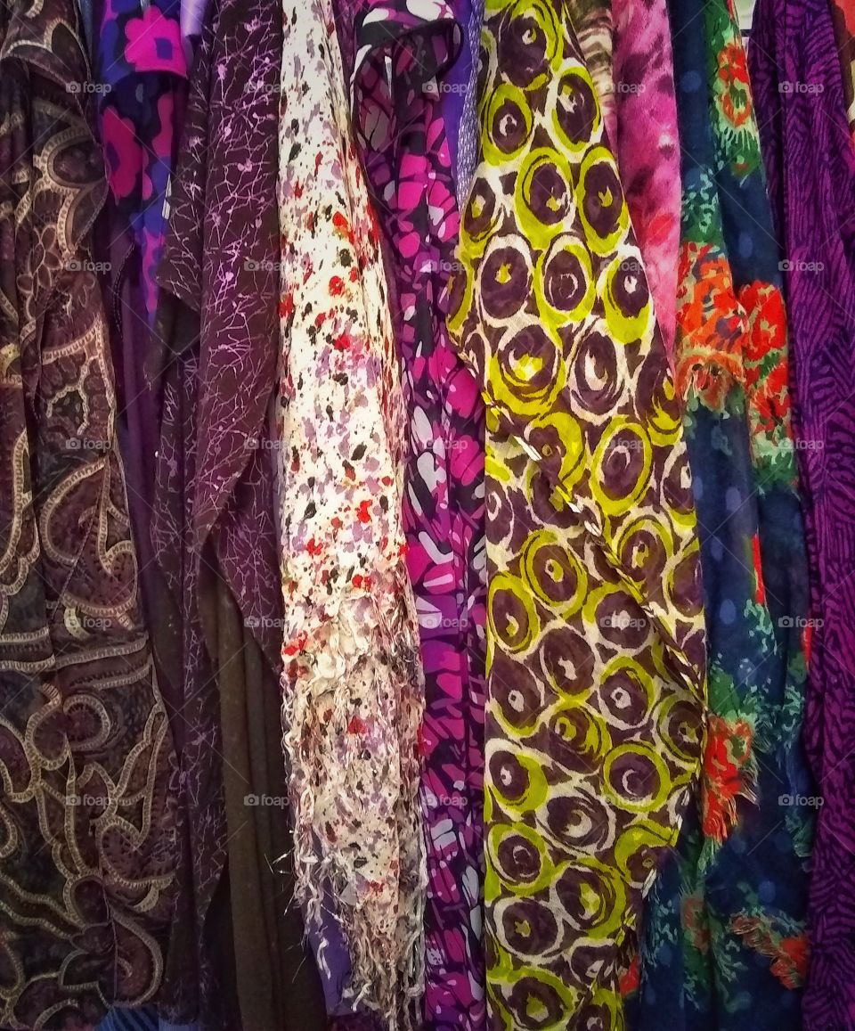 Vibrant colors and patterns print textures on fabric scarves hanging for sale in market