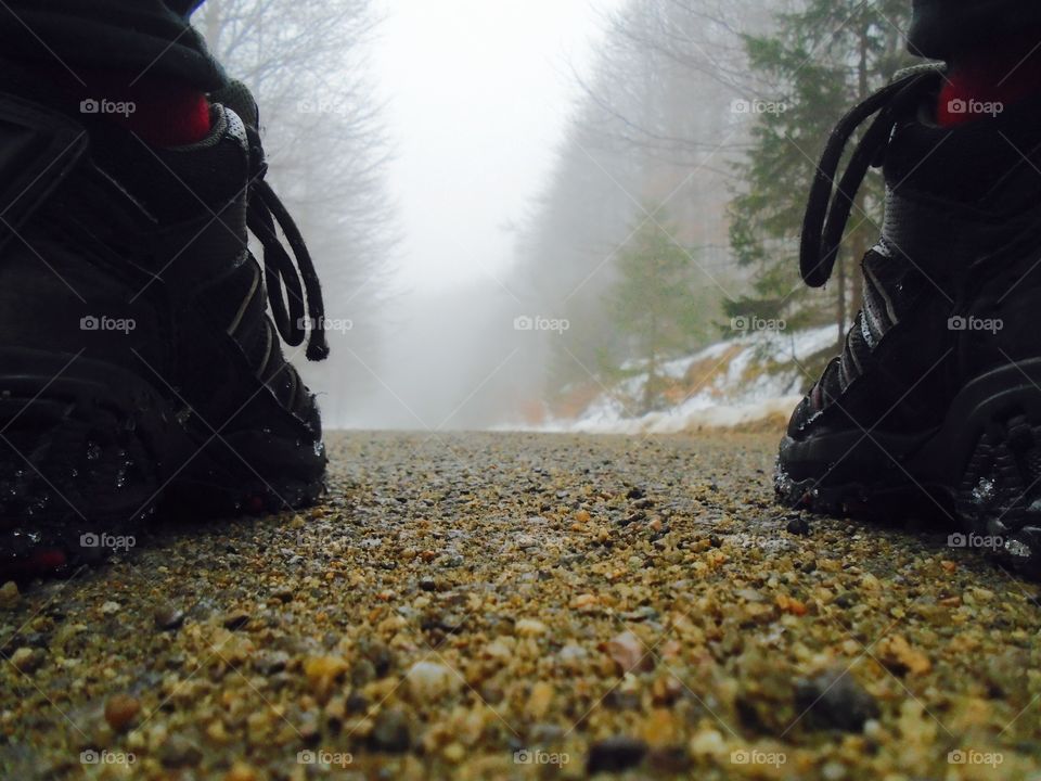 Focus on mountain boots with fog  and snow ahead