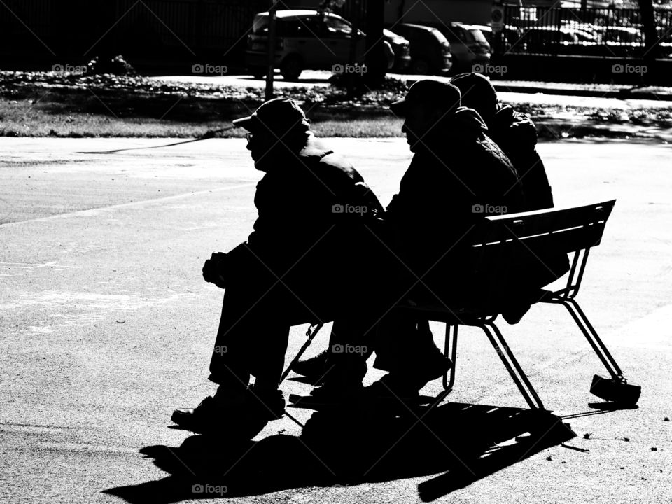 silhouette of elderly men sitting on a bench