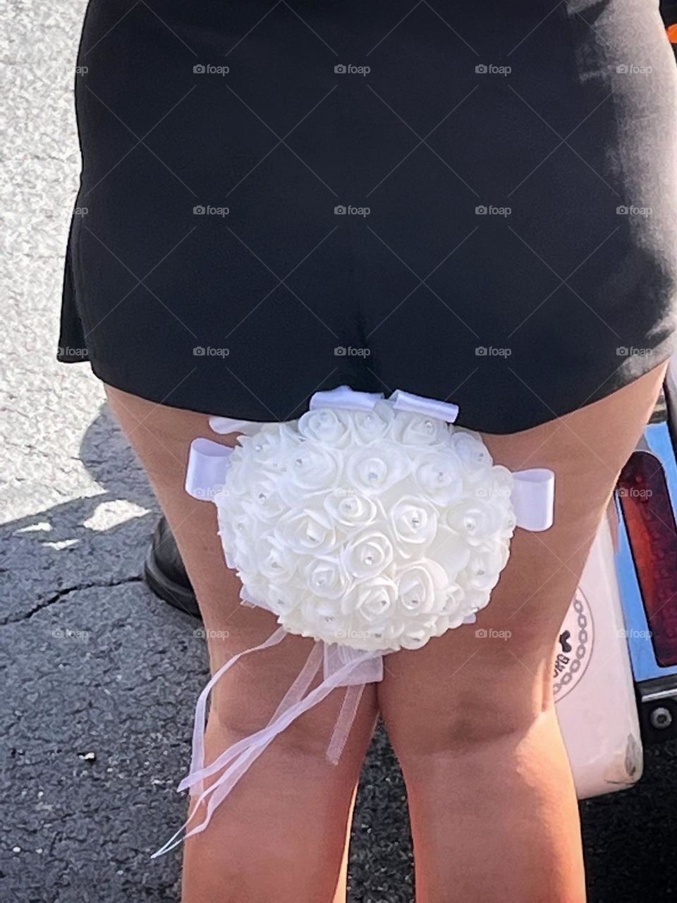 Bridesmaid holding white wedding bouquet between her legs