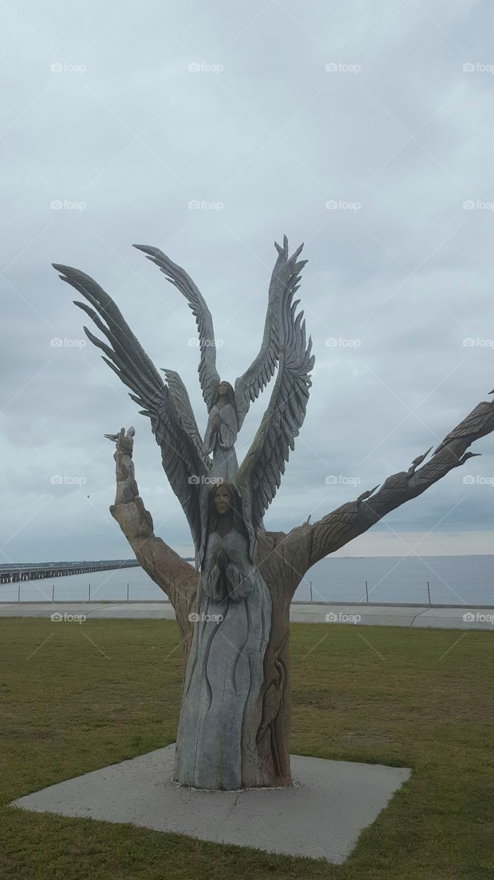 someone carved a tree into this angel statue. so beautiful