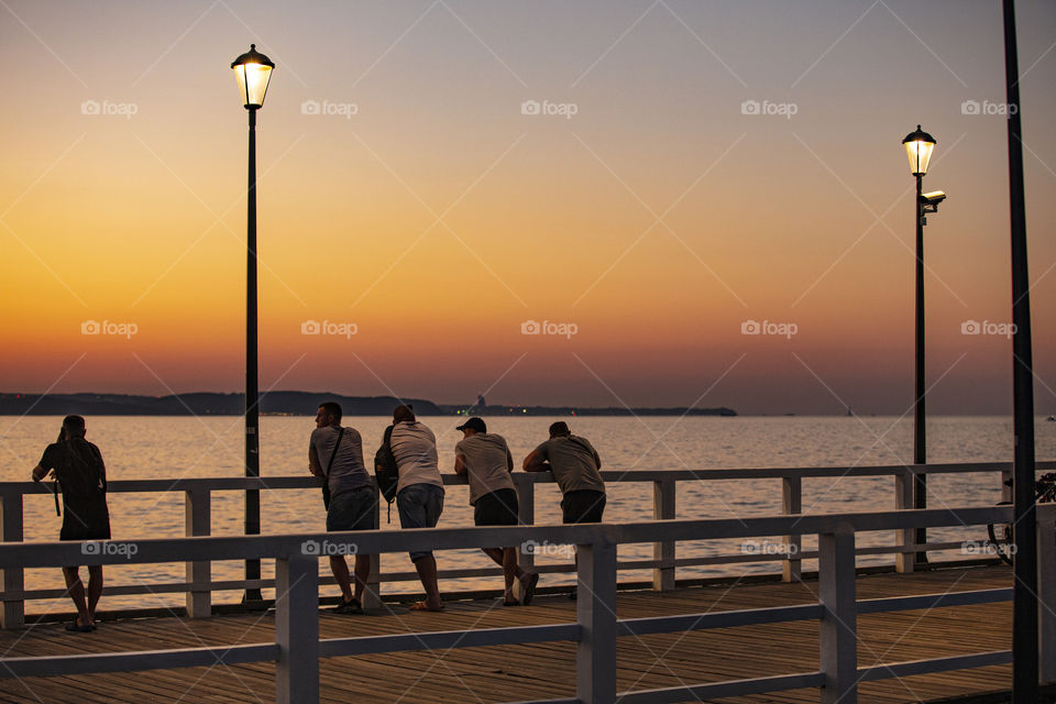 People on pier watching sunset