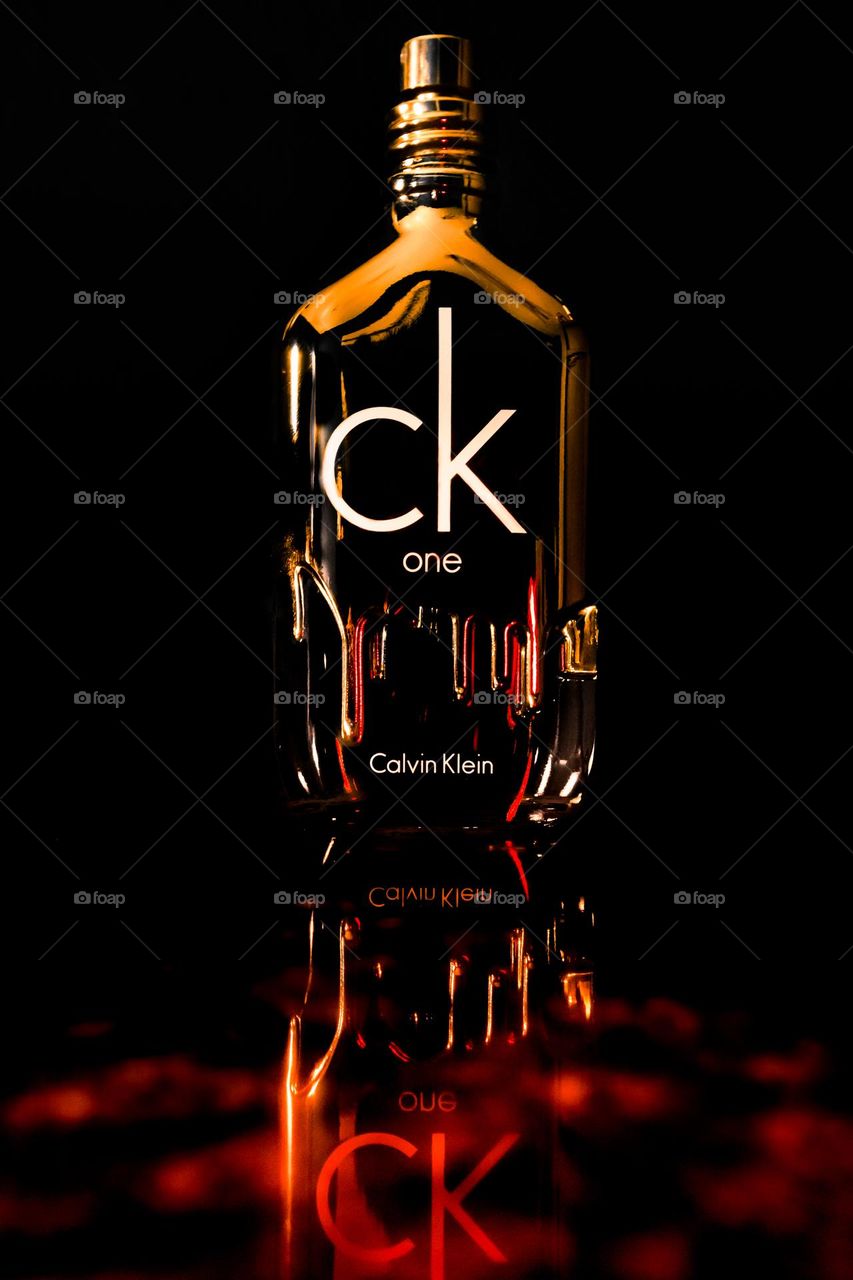 CK one gold Calvin Klein perfume on black background with creative hot red melting theme