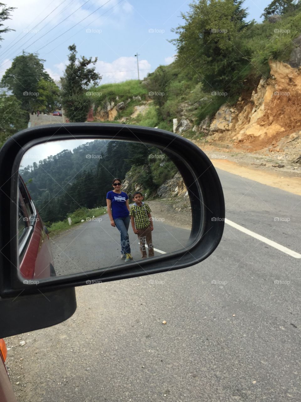 Mother and son reflecting in car mirror