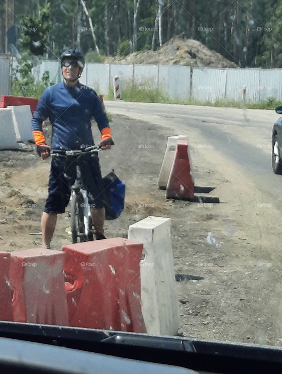 man on a bike waiting for cars to pass by