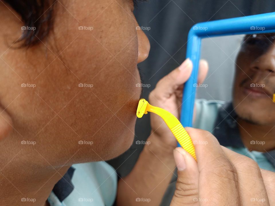 Man is shaving his mustache