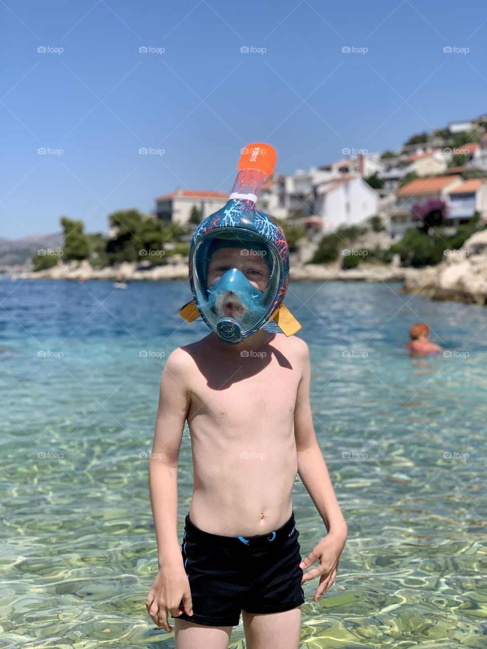 boy in a diving mask against the background of the sea and the old town