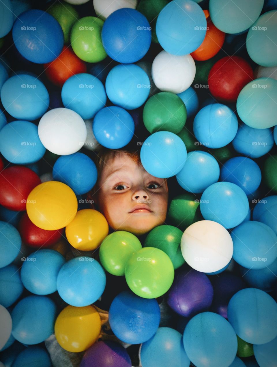 Boy playing hide and seek in a ball pit/ball pool