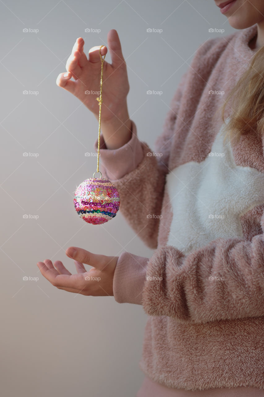 Young girl wearing warm sweater and enjoying her handmade colorful Christmas decoration ball