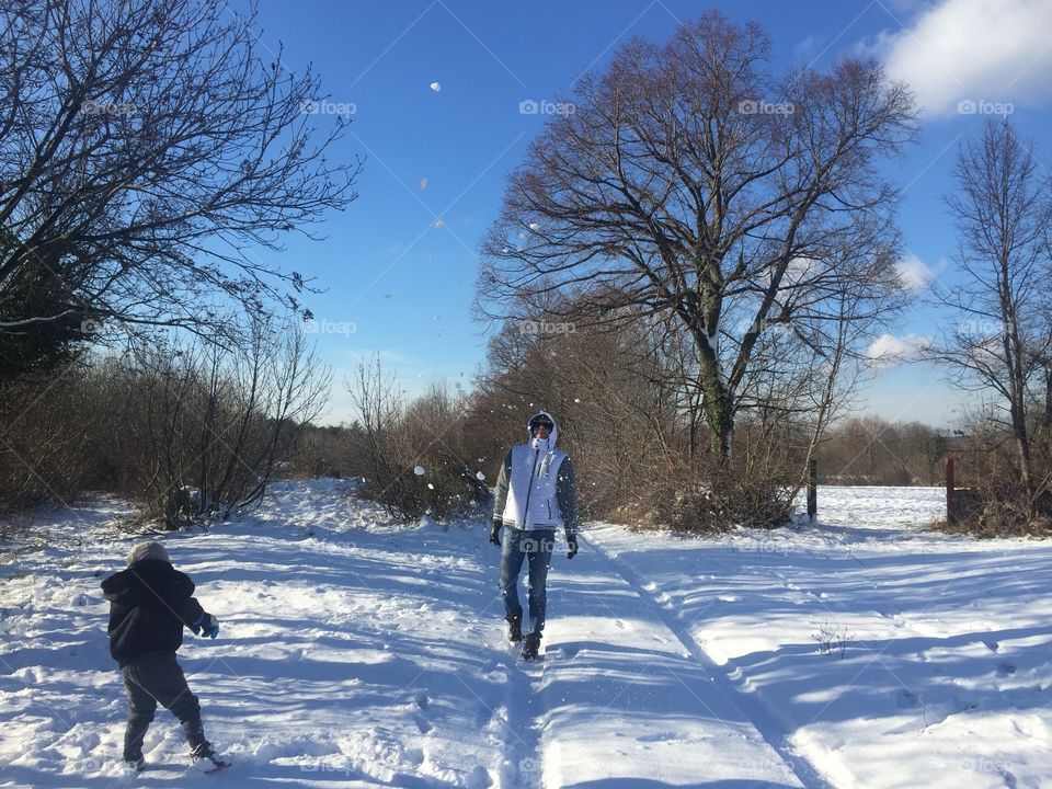 Child playing with father on snowy landscape