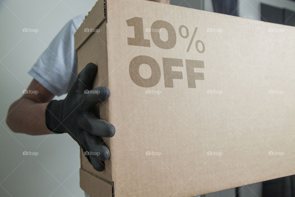 Cardboard box with 10% off order written on the box placed on the floor in an empty room with a neutral background. delivery concept. economy concept. business concept. shopping concept. copy space.