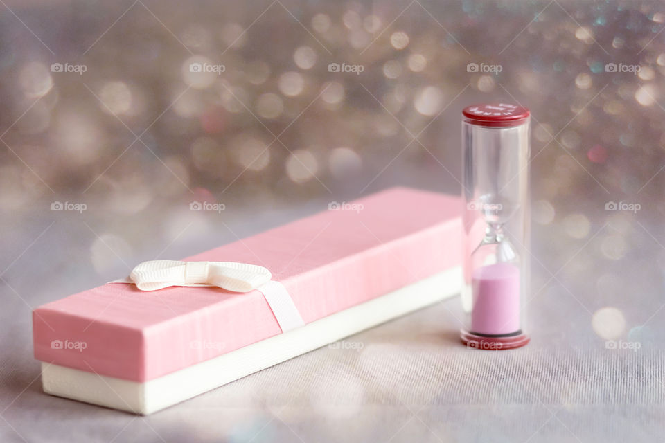 Pink gift box and pink hourglass. Holidays time.