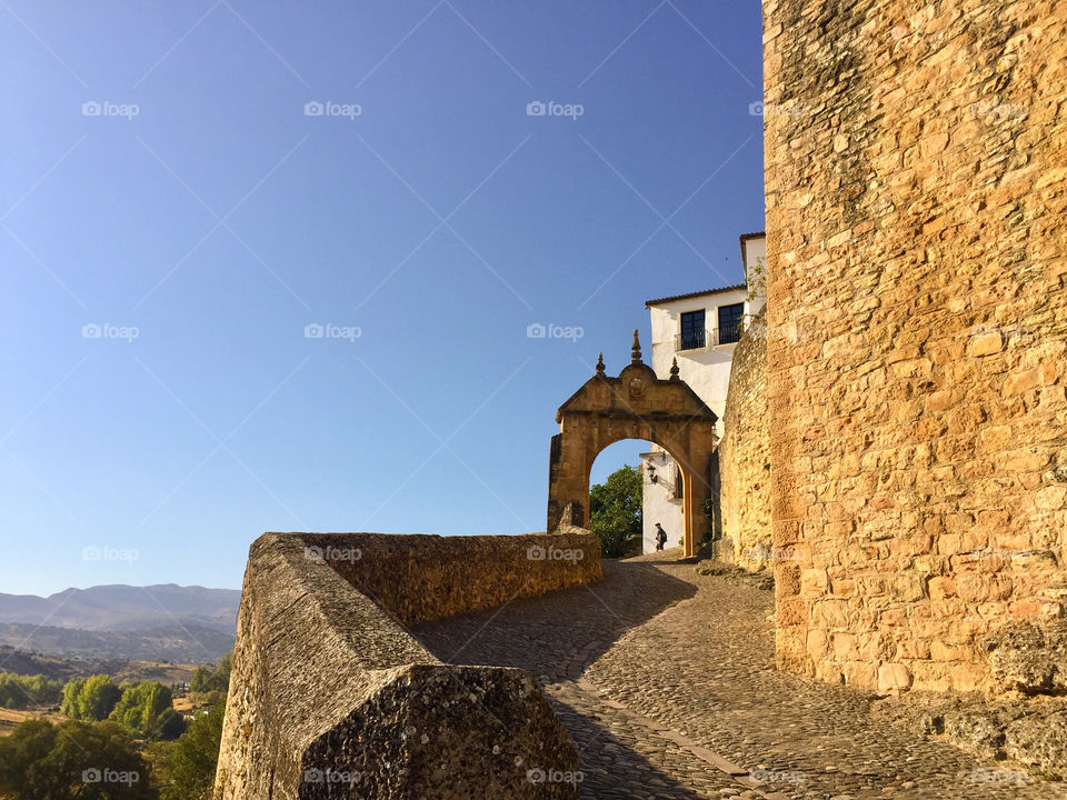 Stone wall and road in a small Spanish village with blue sky