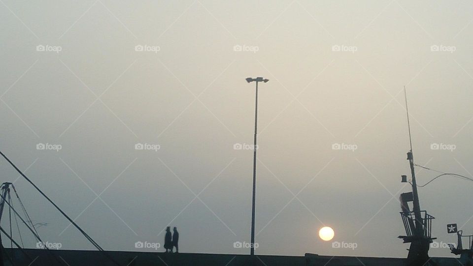 two people walking on wall near the sunset.