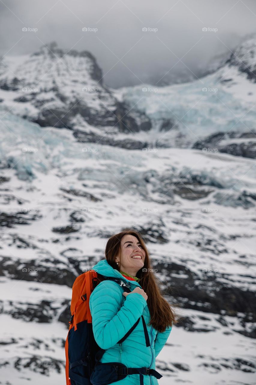 Beautiful woman smiling while hiking on a beautiful mountain region, surrounded by glaciers in Switzerland.