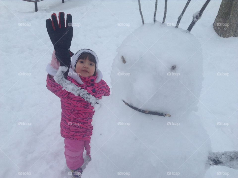 Little girl behind snowman