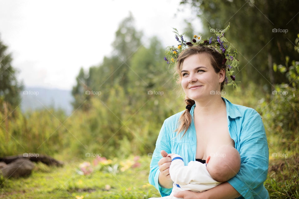 Young mother breast feeding her newborn baby outdoors