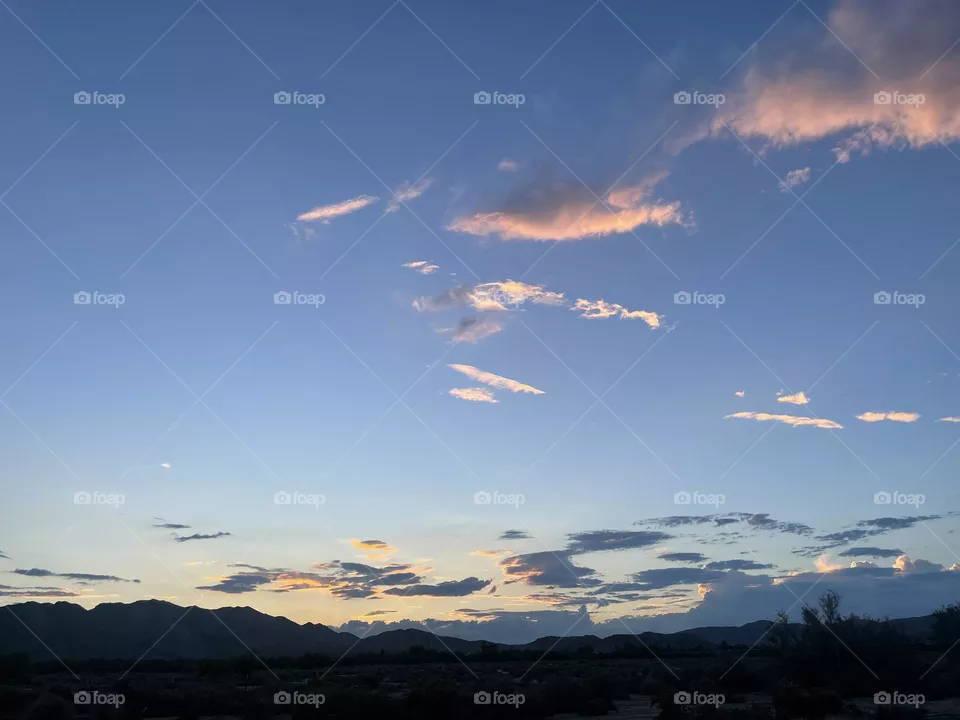 A mountain sunset with pink, and gold clouds. 