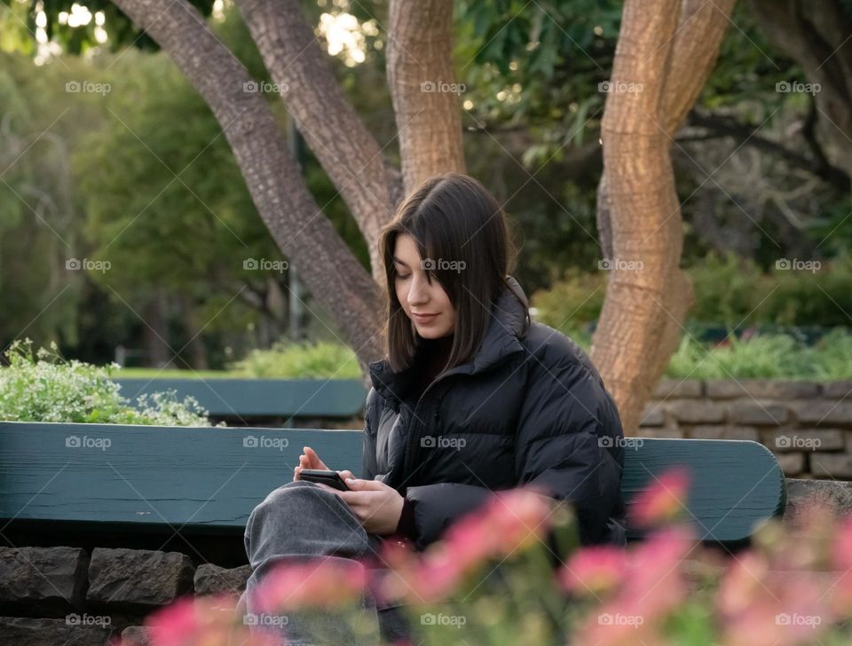 A teenager girl sitting on a park bench 