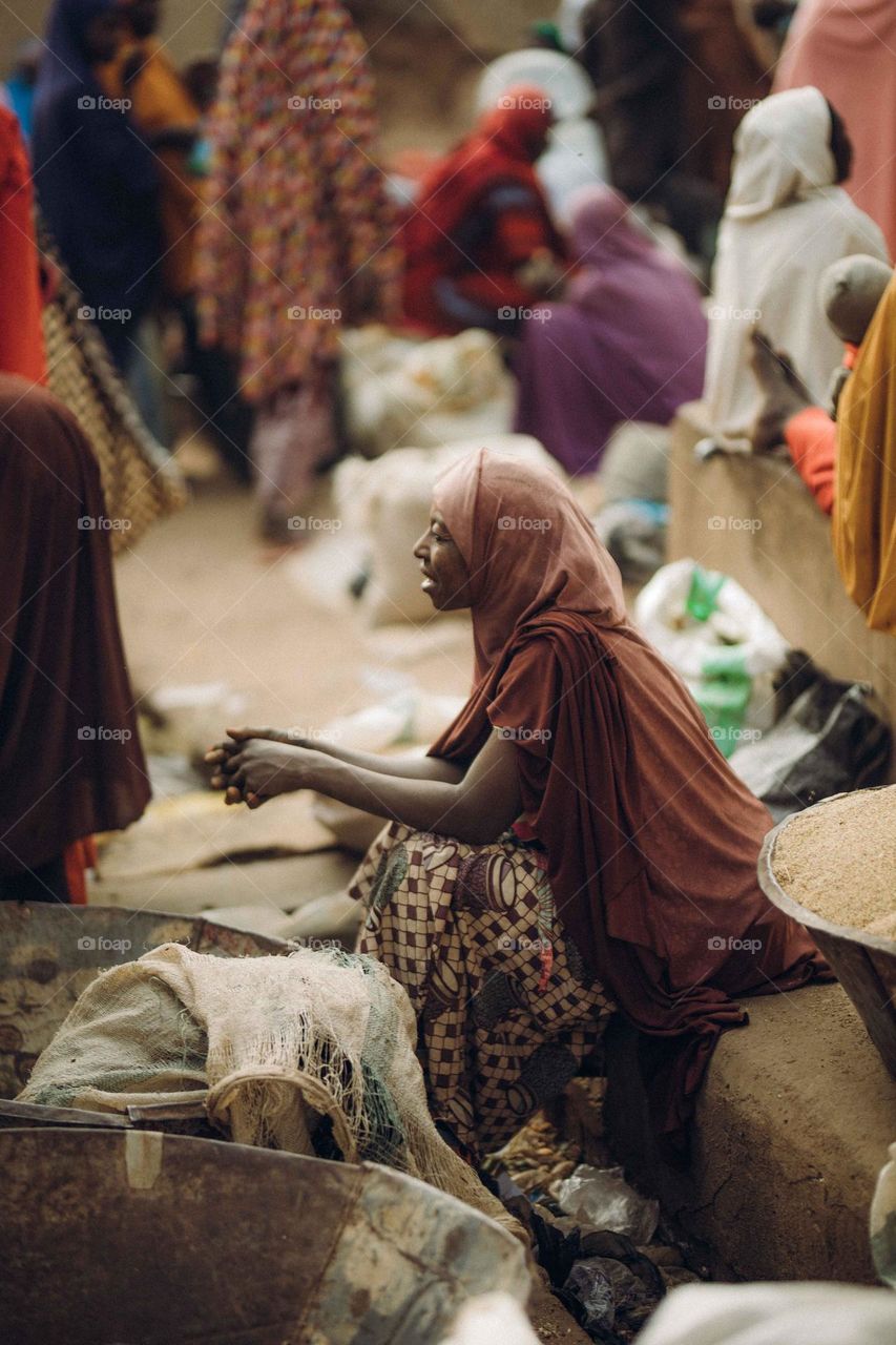 Picture of a old African woman in a northern market sitting and selling crops seed