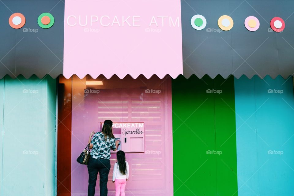 Mother and daughter standing in front of cupcake shop
