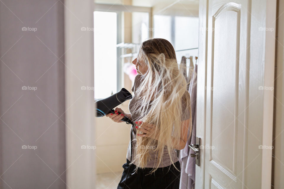 Blonde woman drying her hair in bathroom 