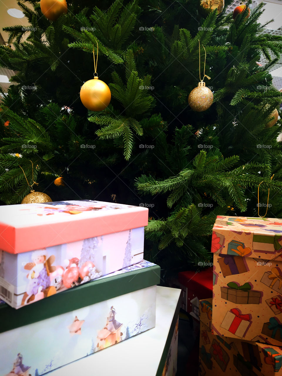 Green Christmas tree with golden balls.  Gift boxes under the tree