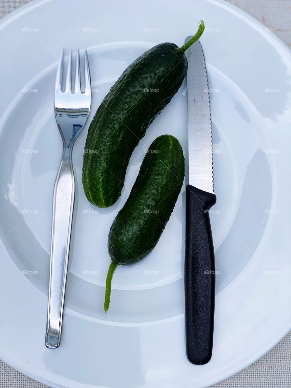 2 Green cucumbers lying on a plate 