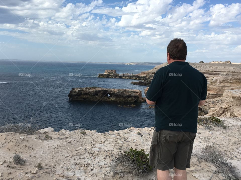 Man standing on beach cliff looking at ocean view