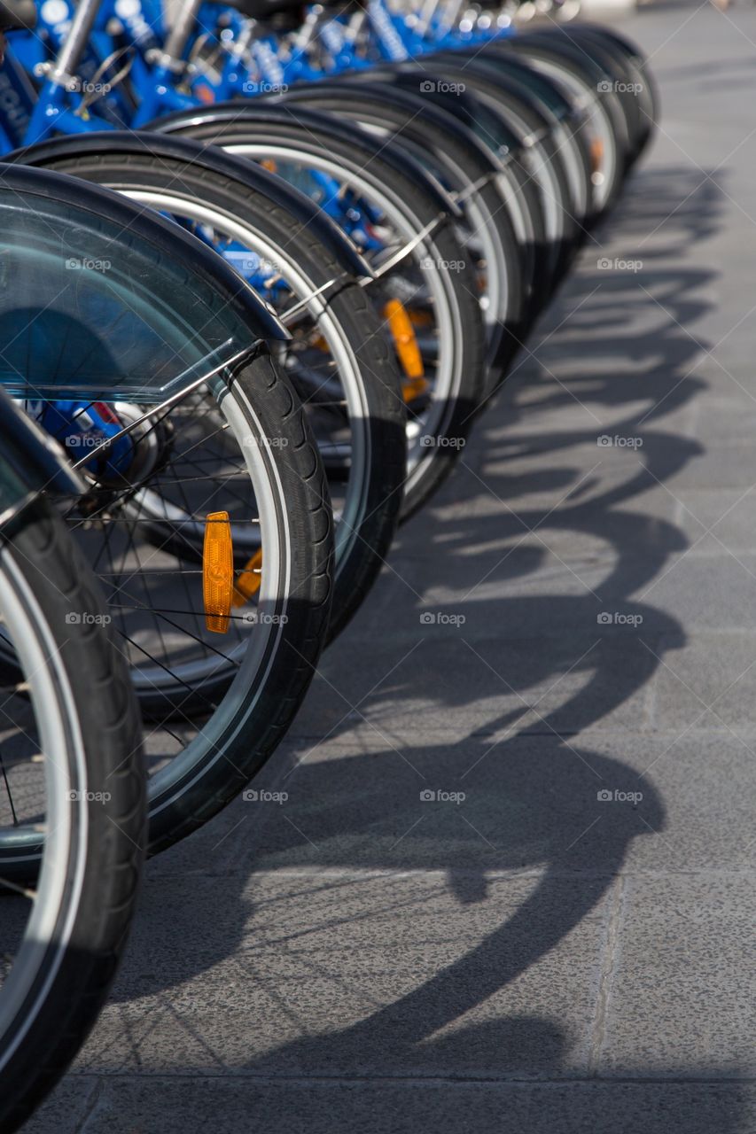 Line of blue bicycles. Line of parked blue bicycles. Close-up for rear tires