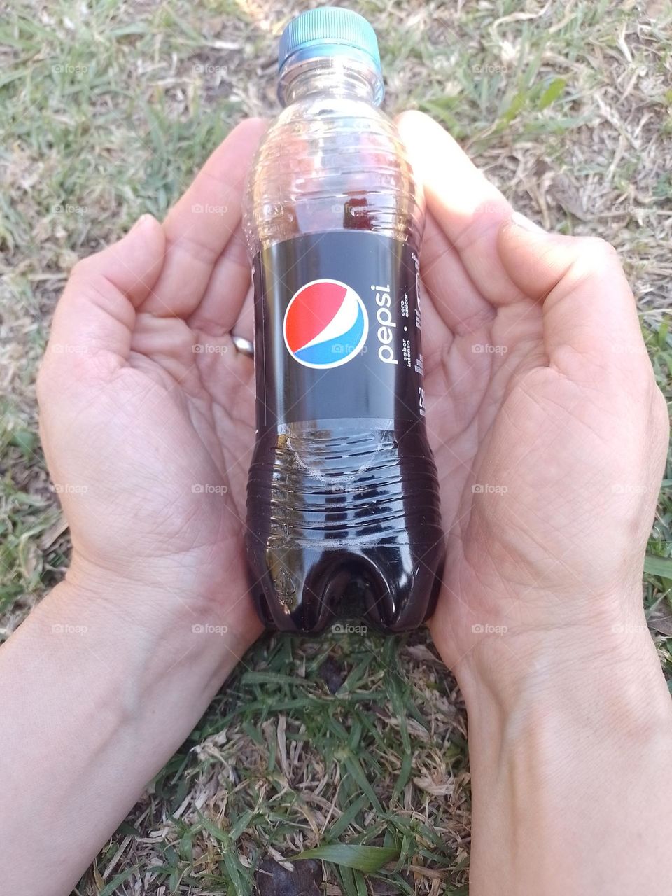 manos agarrando un mini pespi en pasto