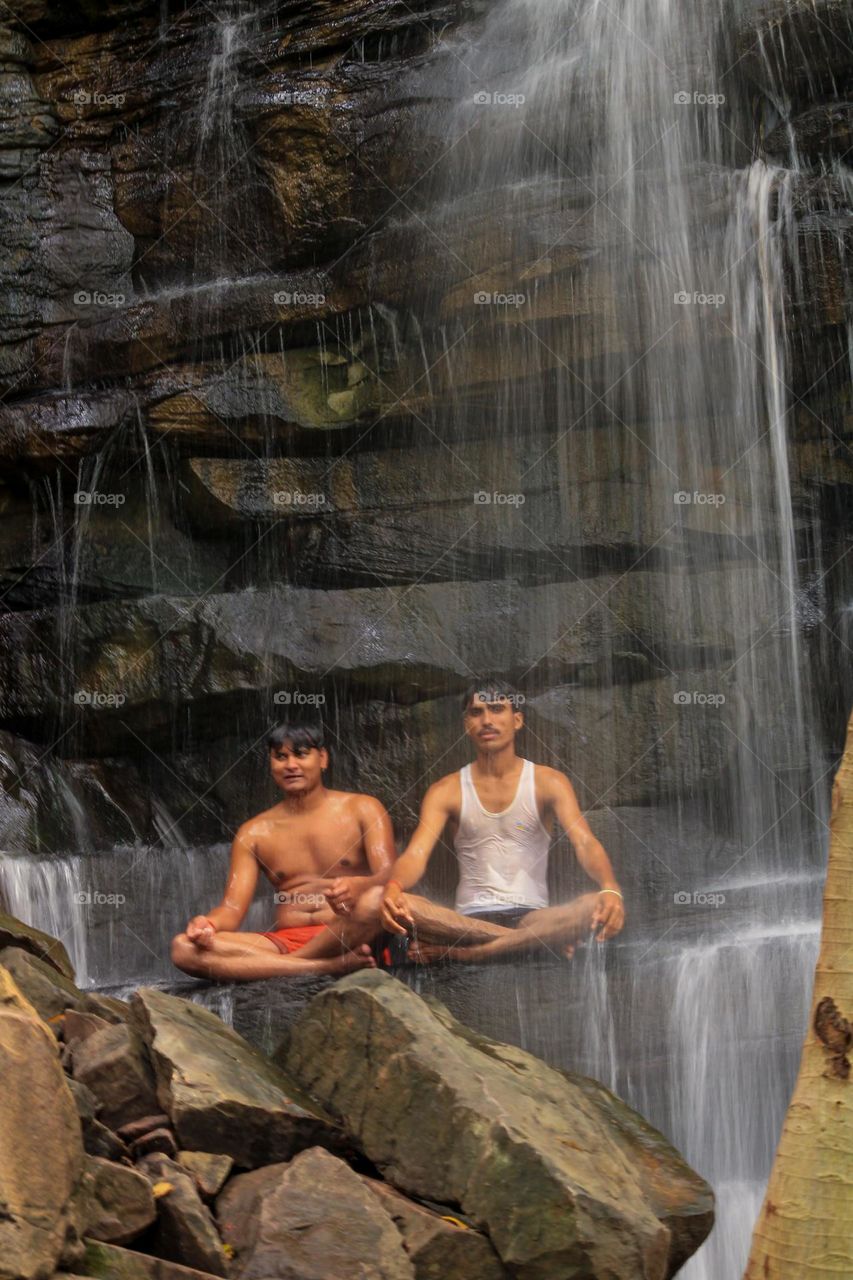 People sitting in mudra position under a waterfall