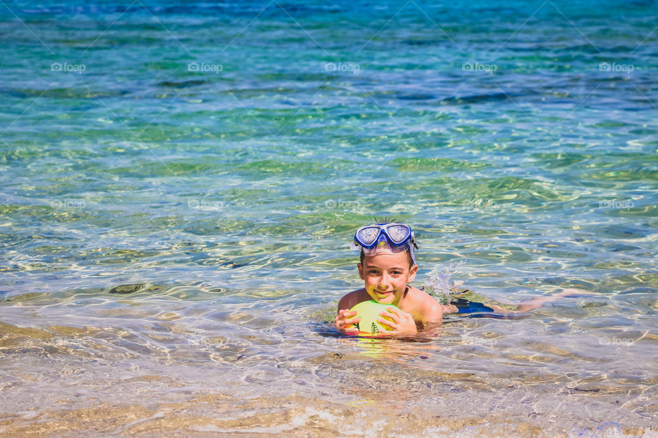 Child have fun with ball in the sea water   Summertime, summer moments and happiness.